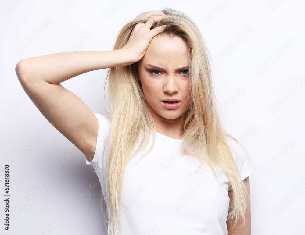 Young woman clutching her head with her palms while suffering from a migraine. Young woman clutching her head with her palms while suffering from a migraine.