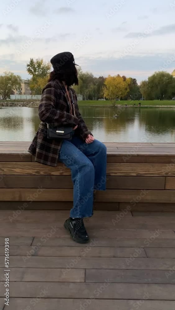 woman sitting on the bench at city park near lake woman sitting on the bench at city park near lake