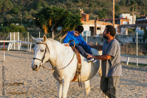 Boy with a disability sitting on a horse during an assisted equine therapy session.