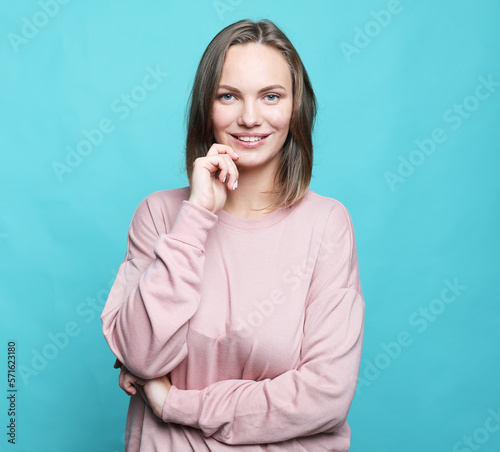 charming smiling young woman dressed pink sweater over blue background