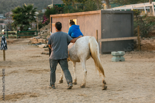 Boy with a disability riding a horse during an equine therapy session.