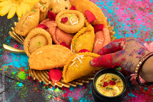 Hands Of A Girl Painted With Colorful Gulal Holding Delicious Gujiya Also Called Gujia, Ghughra, Karanji, Somas, Garijalu, Kajjikayalu, Karigadubu, Gunjiya, Pedakiya, Karjikayi During Holi Celebration photo