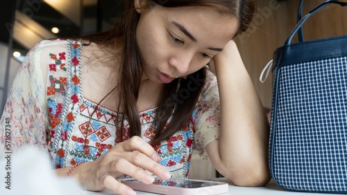 beautiful young lady was thinking while supporting her head. she looked distressed reading the message on her phone