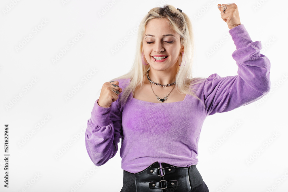 Young blonde girl smiling happy wearing lilac ribbed blouse isolated over white background We did it! closed eyes and wide open mouth. Very happy and excited doing winner gesture with arms raised.