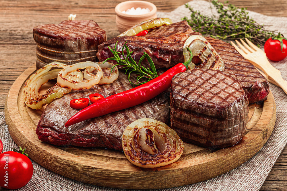 Grilled set of various steaks with vegetables. Ribeye, eye round, flank and striploin steaks Grilled set of various steaks with vegetables. Ribeye, eye round, flank and striploin steaks
