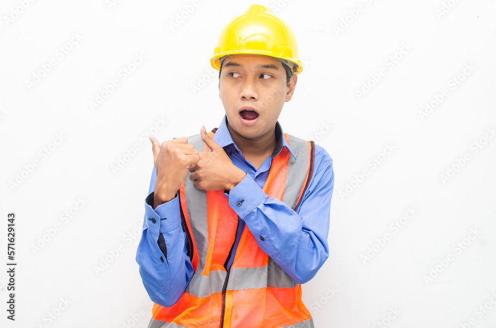 asian construction worker wearing yellow safety helmet and vest smiling and pointing finger with happy and shocked expression. billboard model advertisment concept. asian construction worker wearing yellow safety helmet and vest smiling and pointing finger with happy and shocked expression. billboard model advertisment concept.