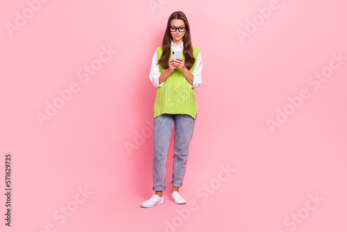 Full length photo of nice cheerful girl straight hairstyle dressed green vest typing email on phone isolated on pink color background