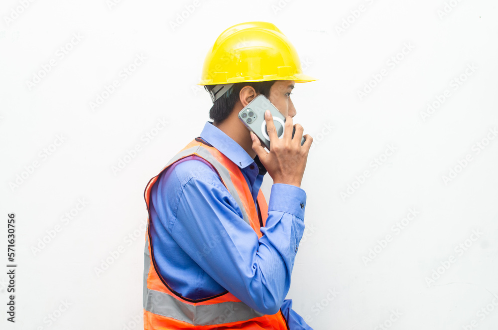 attractive young Asian male construction worker or engineer wearing an orange safety vest and a yellow hardhat holding a phone with shocked, surprised, and amazed expressions. 