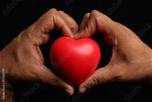 Asian dark skin top view two hand holding making red hart love shape sign on black background