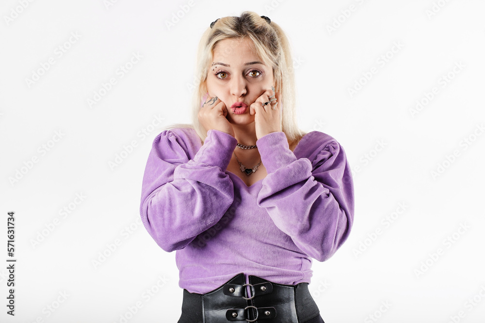 Portrait of blonde woman wearing blouse standing isolated over white background hands in fists, touching chin, looks wow mouth at the camera and is dumbfounded. Can't wait to share what has heard. Portrait of blonde woman wearing blouse standing isolated over white background hands in fists, touching chin, looks wow mouth at the camera and is dumbfounded. Can't wait to share what has heard.