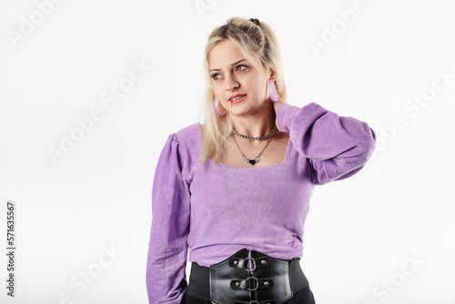 Portrait of young blonde woman standing isolated over white background touching neck feeling pain and numbness, worried about muscle tension, osteochondrosis. Unhealthy. Doesn't exercise and take care