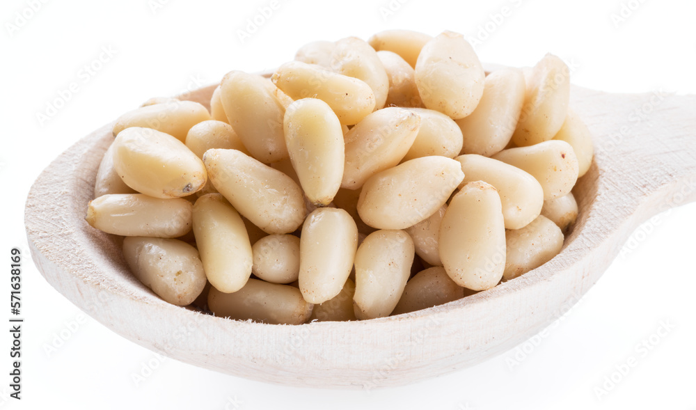 Pine nuts in the wooden scoop. White background.