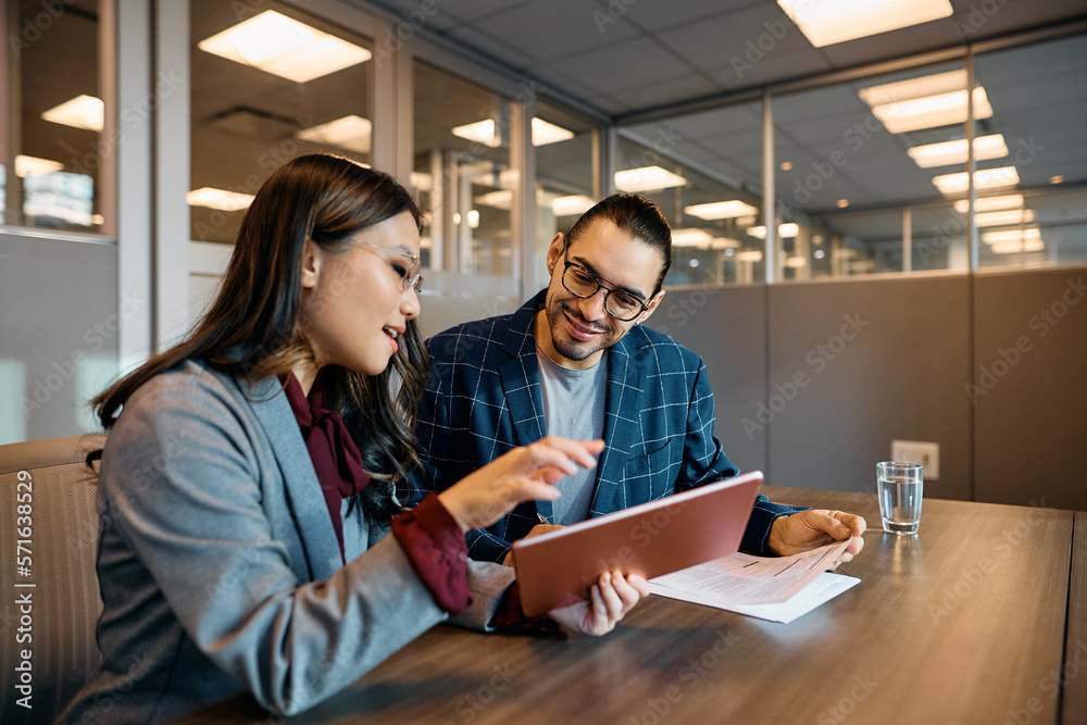 Happy coworkers using digital tablet while working in office. Happy coworkers using digital tablet while working in office.