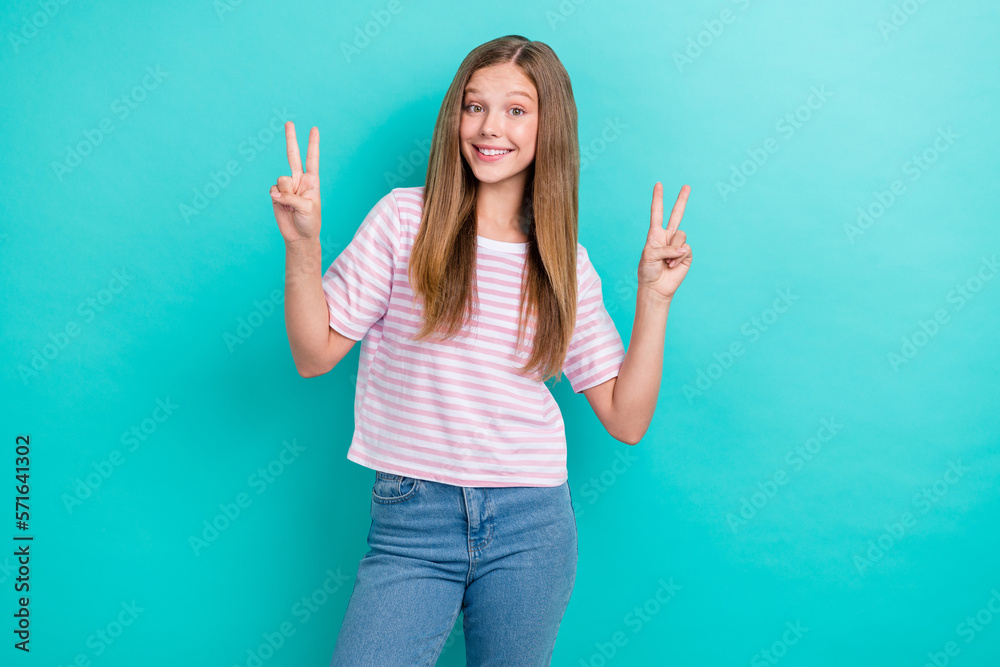 Photo of positive cool girl dressed pink t-shirt smiling showing v-signs isolated teal color background Photo of positive cool girl dressed pink t-shirt smiling showing v-signs isolated teal color background