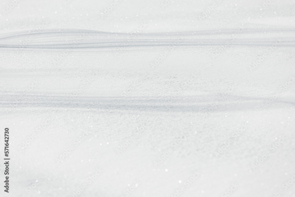 Obraz premium Photo of snow cover with smooth trees shadows on it under warm sunlight on the winter, some snowflakes is shining on a sun. Wintertime atmosphere with white snow.
