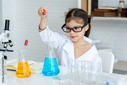Little Asian girl sitting in the science room Learning science, practical, squeezing water from a flask into a beaker as specified by the teacher as a score fun to experiment