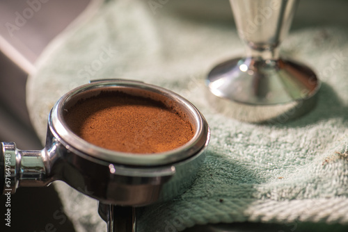 Tamped espresso finely ground coffee from coffee grinder grinds freshly roasted coffee beans with a tamper. Fine coffee pressed by tamper.