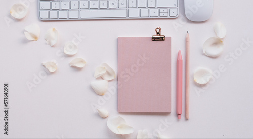 Desk with keyboard and mouse, notebook, clip, pen, pencil, decorated with white rose petals, pink touch