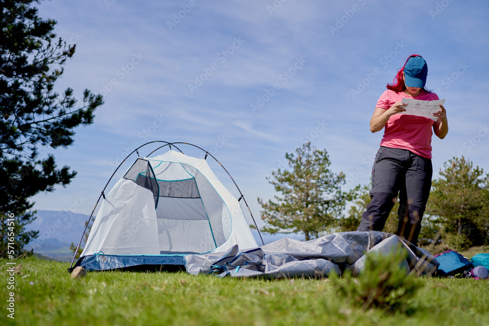 Backpacker woman setting up a tent outdoors in nature. Camping and adventure concept.