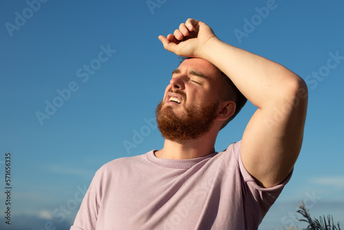 Cuadro en lienzo portrait of tired sick exhausted man, handsome guy is suffering from hot Summer heat stroke, sunshine, hot weather day, sweaty and thirsty, high temperature