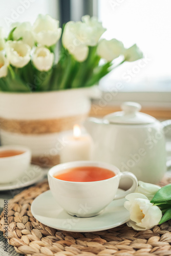 Cup with tea close-up, tulips and a candle, atmospheric photo