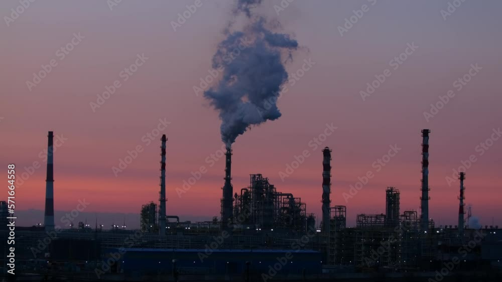 Working oil refinery. Smoke from the factory chimney. Ecological pollution. Air emissions polluting the city. Industrial waste is hazardous to health. A large working factory in the smog at sunset. Working oil refinery. Smoke from the factory chimney. Ecological pollution. Air emissions polluting the city. Industrial waste is hazardous to health. A large working factory in the smog at sunset.