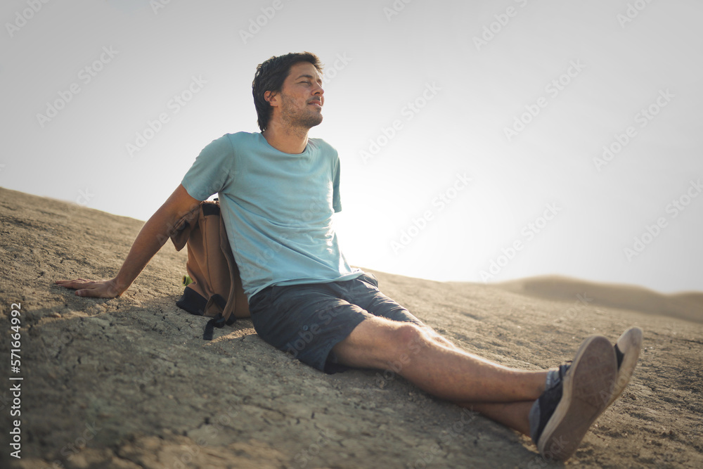 white man sitting on the ground in a desert