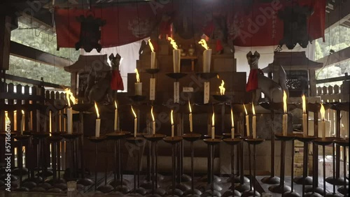 This video shows an Inari shrine with lit incense and candles blowing in the wind in slow motion.