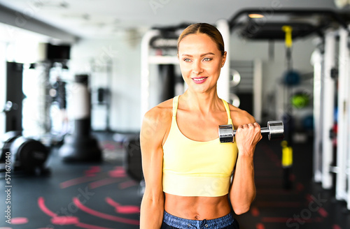 Beautiful young woman lifting dumbbells in a gym