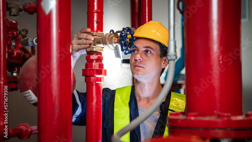 A team of engineers is examining the plumbing and water valves inside an industrial facility.