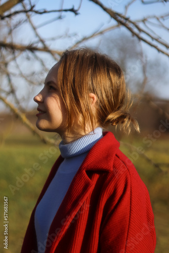 Portrait of a young woman in profile.Girl on the street.Positive gentle calm emotions.Woman in red.Warm tones.Blonde hair in a bun.Beautiful girl.Sunlight.Retro and vintage.Ukrainian.Woman smiling.