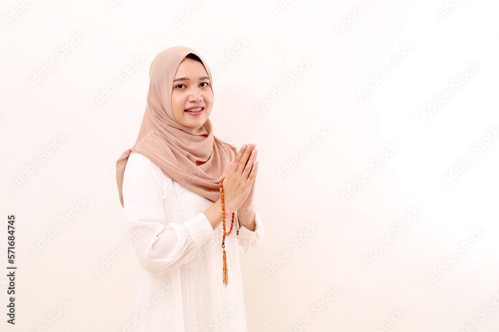 Portrait of young asian muslim woman standing with praying gesture while holding prayer beads Portrait of young asian muslim woman standing with praying gesture while holding prayer beads
