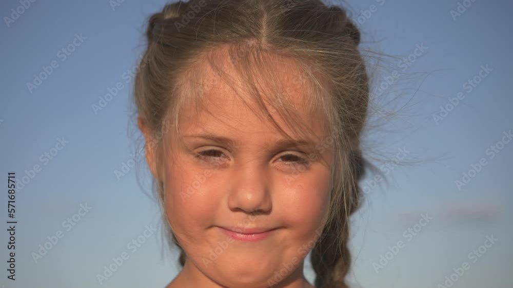 Portrait of happy smiling girl in park. Laughing child. Expressive facial expressions. Cute little girl smiles at camera against background of sky. Happy smiling child enjoying life in park. Portrait of happy smiling girl in park. Laughing child. Expressive facial expressions. Cute little girl smiles at camera against background of sky. Happy smiling child enjoying life in park.