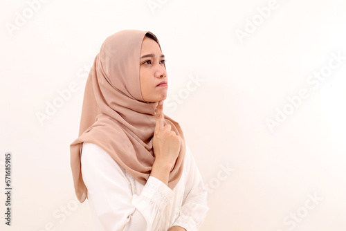 Side view of young asian muslim woman thinking something while looking above on blank space