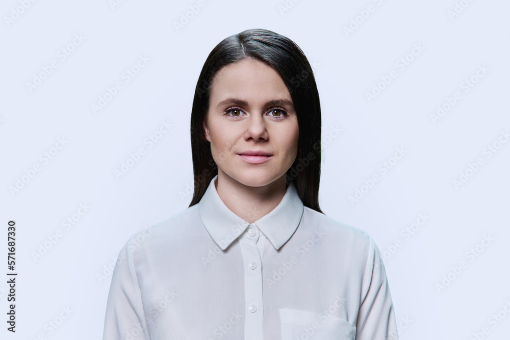 Headshot portrait of young woman looking at camera on white background Headshot portrait of young woman looking at camera on white background