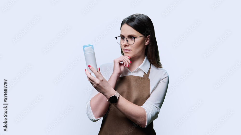 Young woman beautician holding tube of cream lotion, cosmetic product Young woman beautician holding tube of cream lotion, cosmetic product