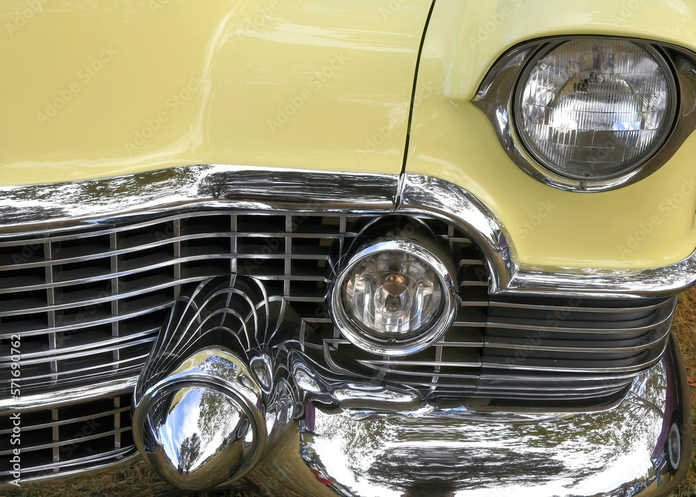 Closeup of the grill of a yellow 1950's luxury automobile