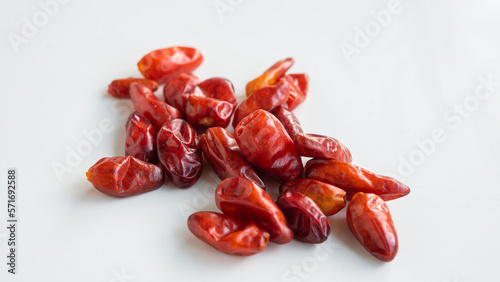 Close up of dried up pequin peppers on white background.