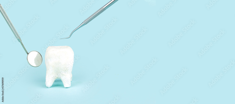 White molar on blue background. Big tooth model and different tools for ...