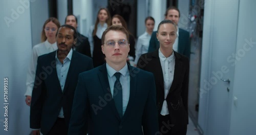 team of multiethnic businesspeople walking in office center corridor, frontal view, 4K, Prores
