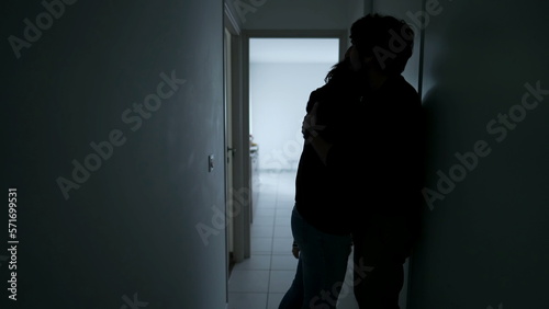 Silhouette of Man embracing woman standing in home corridor. Young Couple going through hard times. Husband and wife hugging during depression. Support and counseling concept