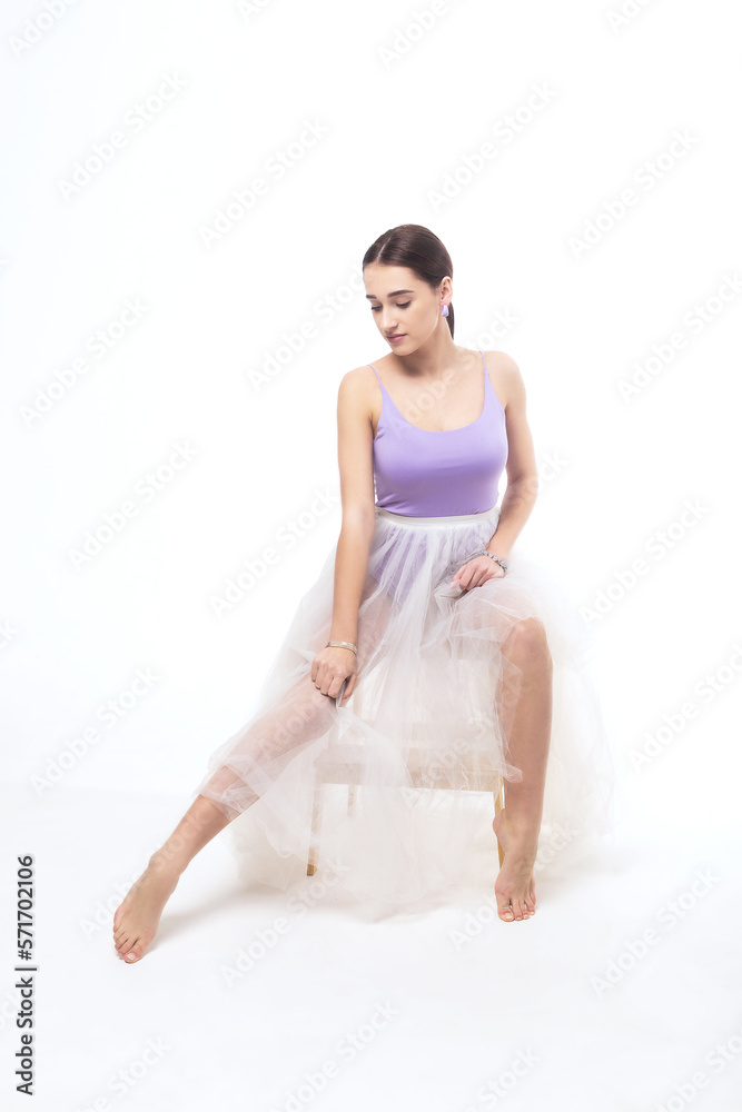 Young woman in a tulle skirt posing on a white background Young woman in a tulle skirt posing on a white background