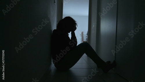 Depressed woman sitting on floor. Sad unhappy person holding her forehead suffering from mental illness photo