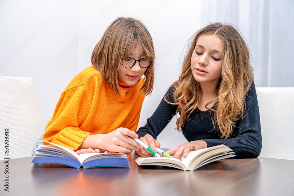 two young girls, sisters are preparing homework with books. children of generation z two young girls, sisters are preparing homework with books. children of generation z