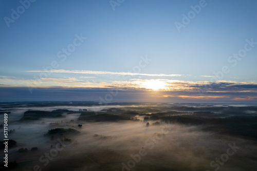 Foggy morning on a beautiful lake surrounded by forests and fields. A small village located near a lake in fog and morning sun.