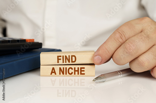 In the hands of a businessman, wooden blocks with the inscription - Find a niche