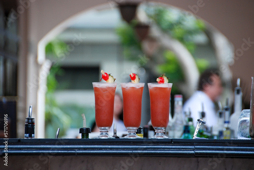 Wall Mural Three cocktail glasses with Singapore sling drinks on a bar in the Raffles hotel