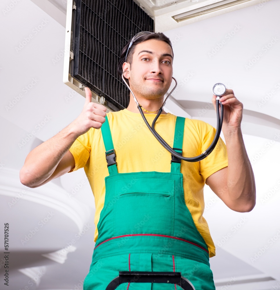 Young repairman repairing ceiling air conditioning unit Young repairman repairing ceiling air conditioning unit