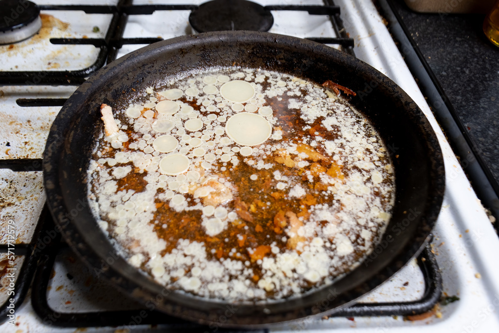 Dirty frying pan, full of water fat and grease.