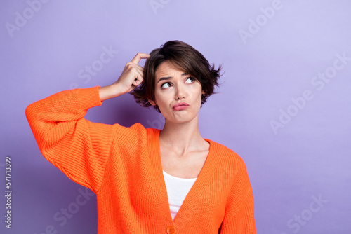 Photo of doubtful unsure lady dressed orange cardigan finger head looking empty space isolated purple color background photo